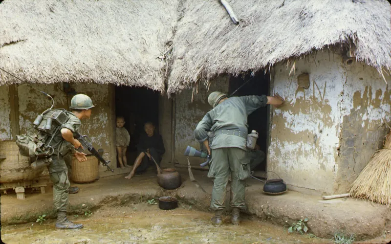 Lính Mỹ lục soát Việt Cộng trong một ngôi nhà ở vùng quê Quy Nhơn, năm 1966. Các chiến dịch "bình định" khiến hơn 130.000 người dân địa phương phải chạy lánh nạn vào các trại tị nạn.