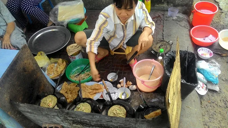 Người bán ''bánh xèo'' dạo nấu trên than nóng ngoài đường